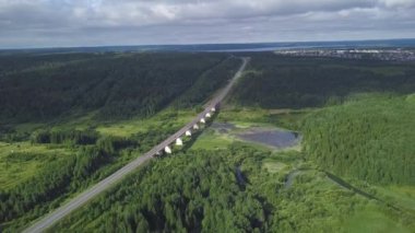 Üstten görünüm köprünün ormanda geçiyor. Küçük. Otoban bataklık orman içinde şehre ufukta geçer. Bulutlu hava kırsal otoyol trafik