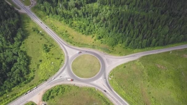 Bovenaanzicht van landelijke rotonde. Clip. Verkeer op rotonde landelijke weg in bosrijke omgeving — Stockvideo