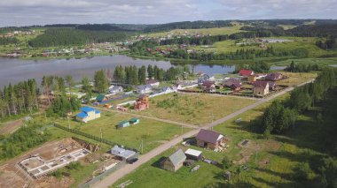 Üstten görünüm Orman Köyü. Küçük. Köyden yazlık yürüyüş için adam geliyor. Köy yaşamı ormandaki modern evler ile