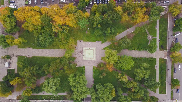 Top view of city park. Clip. Small park in city center with number of cars standing in parking lot. Ecological park in city in autumn.
