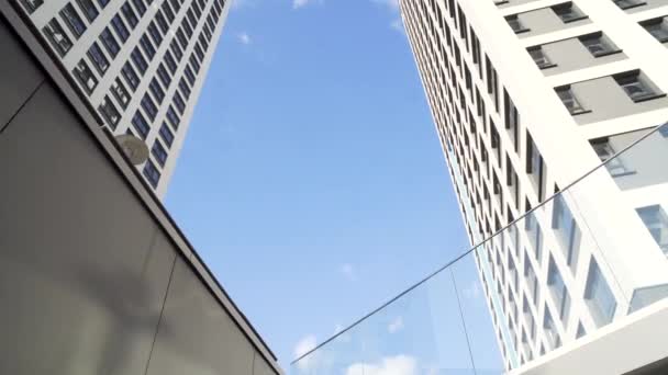 青い空を背景に近代的なオフィスビル群のグループを見上げてください。フレーム。日当たりの良い日中は、低角度表示ガラス都市の建物. — ストック動画