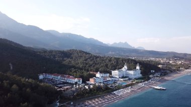 Video. Otelin deniz ve dağlar havadan görünümü ile yeşil orman, blue sky adlı gündoğumu ağaçlarıyla kaplı. Video. Lüks Otel ile orman ve dağlar bir arka plan ile sahil üzerinde havadan görünümü