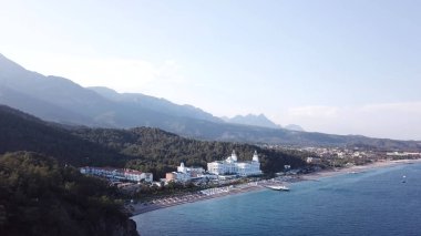 Video. Otelin deniz ve dağlar havadan görünümü ile yeşil orman, blue sky adlı gündoğumu ağaçlarıyla kaplı. Video. Lüks Otel ile orman ve dağlar bir arka plan ile sahil üzerinde havadan görünümü