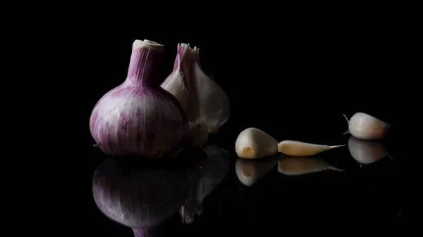 Onions and garlic over black background. Still-life of onions and falling garlic on black background