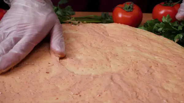 Lägga till sås. Italiensk pizza beredning. Ram. Ost som sprids på tomatsåsen på pizzabotten. Närbild hand kock Baker i vit uniform att göra pizza på kök — Stockfoto