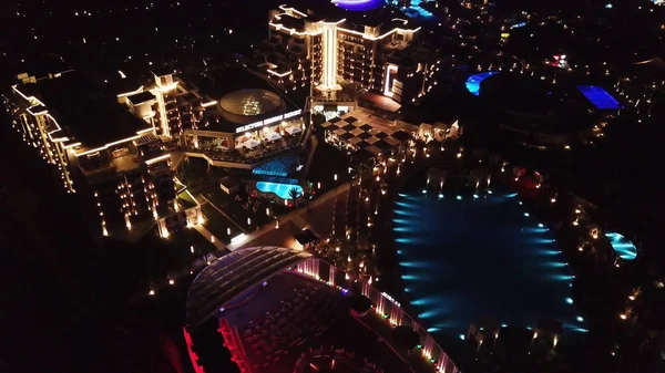 Letecký pohled na luxusní resort hotel je dobře situován v noci. Video. Noční pohled na osvětlené vnitřní území hotelový komplex s chodníky, palmami a bazénem. Tropický resort v noci horní zobrazit. — Stock fotografie