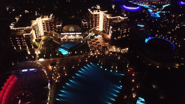 Vista aérea sobre el territorio del hotel resort de lujo por la noche. Vídeo. Vista nocturna del interior iluminado del complejo hotelero con senderos, palmeras y piscina. Hoteles tropicales en la noche vista superior . — Foto de Stock