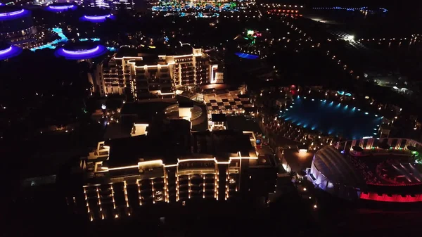 Aerial view on luxury resort hotel territory at night. Video. Night view of illuminated inner territory of hotel complex with footpaths, palms and pool. Tropical resort hotels at night top view. — Stock Photo, Image