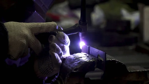 Iron welding with bright light and smoke at manufacturing. Clip. Industrial worker man at the factory welding close up by arc