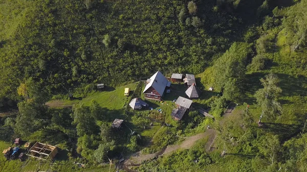 Вид с воздуха на маленькую деревню в горах, лесной фон. Горный пейзаж с деревней, вид сверху. Клип . — стоковое фото