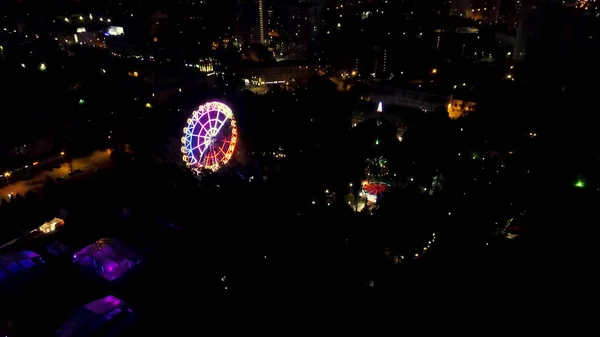 Vista aérea nocturna del horizonte de la ciudad y la rueda de los hurones. Vista superior de la noria Rueda en el parque central por la noche. Clip . —  Fotos de Stock