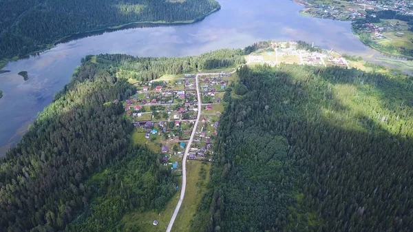 Luftaufnahme aus der Drohne: Flug über Herbstdorf mit Straße mitten im Wald. Clip — Stockfoto