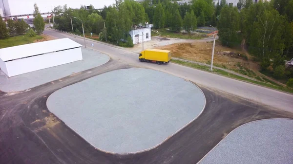 Aerial View of Loading Warehouse with Semi Truck. Clip. Aerial Top View of Trucks with Cargo Semi Trailer Moving on the Road in the Direction of Loading Warehouse Area. Aerial view of trucks unloading