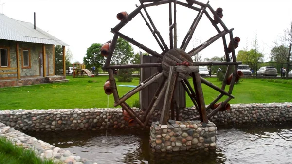 Pabrik air kayu tua di halaman desa. Pabrik air kayu kecil berputar di kolam kecil, dekorasi di taman. Kincir air di taman dihiasi — Stok Foto