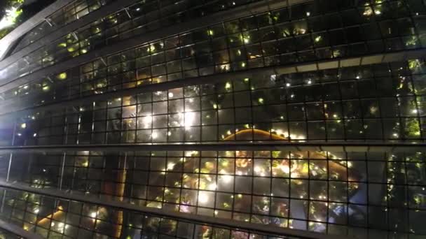 ガラスのファサードを有するビジネス建物の夜窓で明るく美しいライト反射 Windows オフィスビル背景 夜に美しい光の反射 — ストック動画