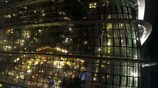 Singapura - 25 de setembro de 2018: reflexo de luzes brilhantes e bonitas nas janelas noturnas do prédio de negócios com fachada de vidro. Atingido. Reflexão luzes bonitas à noite, janelas edifício de escritórios — Vídeo de Stock