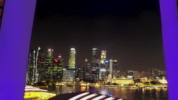 Volando a través de las torres de Marina Bay Sands hasta el hermoso paisaje urbano nocturno y el río de Singapur. Le dispararon. Vista aérea desde Marina Bay Sands Hotel y Singapur por la noche . — Vídeos de Stock