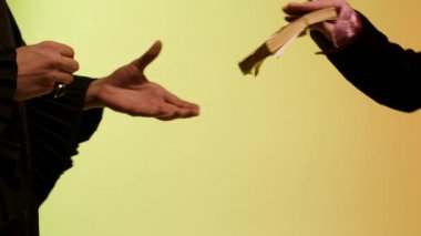 Satıcı için bir tomar para veren Doğu kadın el için kapatın ve yuvarlak, gümüş izle, sarı arka plan üzerinde izole alma zamanı para kavramı. Hisse senedi. Kadın gümüş saatim kağıt para için alır..