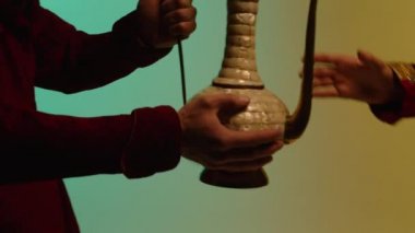 Adam mavi ve sarı zemin üzerine Doğu seramik sürahi antika ürünler satan kavramı veren eller. Doğu, antik, Seramik çay veya şarap sürahisi iletme işlemi.