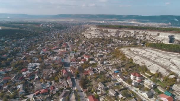 岩の丘に囲まれた町。ショット。山の近くの美しい都市景観の航空写真 — ストック動画