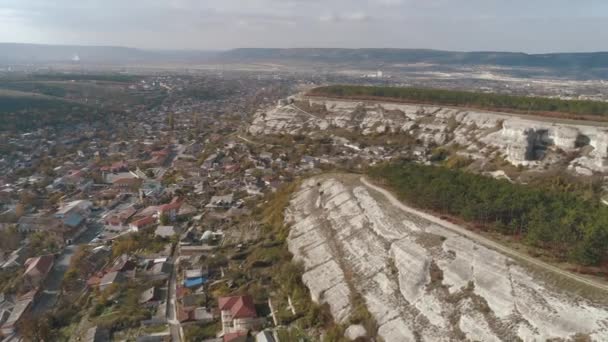 Staden omges av klippiga bergen. Skott. Flygfoto över vackra stadslandskapet nära bergen — Stockvideo