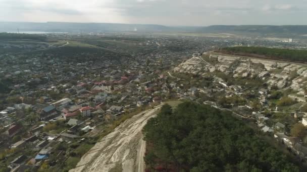 En stad i låglandet nära klipporna omfattas av tallar. Skott. Flygfoto — Stockvideo