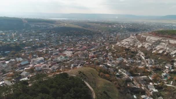 Una ciudad en tierras bajas cerca de los acantilados cubiertos de pinos. Le dispararon. Vista aérea — Vídeos de Stock