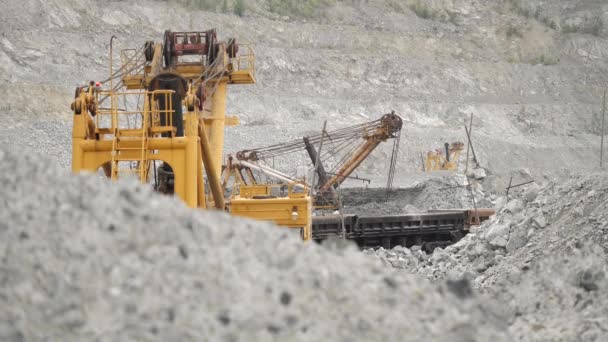 Graafmachine in een steengroeve voor kalksteen mijnbouw beweegt erts in spoor auto's. Mijnbouw. — Stockvideo