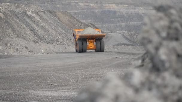 Camión volcado se mueve a lo largo de la carretera cargado de mineral en una cantera. Vista trasera . — Vídeos de Stock