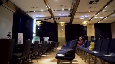 İngiltere - Londra, 10 Aralık 2018: konferans salonu yan görünüm, mavi sandalye satırlarla savaşlar büyük beyaz projektör ekran karşı onlara su. Hisse senedi. İle geniş iş konser salonu