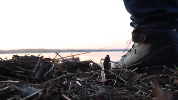 Bakifrån av en man som går in i sjön i höst på sunset oskärpa himmel bakgrund. Närbild för visset, gult, blött gräs och en man bakom gå in kallt vatten i sjön. — Stockvideo