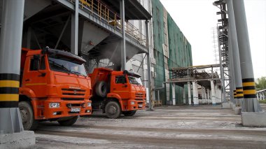 Taşımacılık - depodaki iki kırmızı kamyon. Depolama ve nakliye terminal. Endüstriyel dikey arka plan. Terminal kamyon yükleme, lojistik. Ulaşım - kamyonette yük