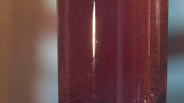 ฟองก๊าซลอยอยู่ในขวดพลาสติกที่มีของเหลวสีน้ําเงินเข้ม ของเหลวสีแดงที่มีฟองในขวดพลาสติก — ภาพถ่ายสต็อก