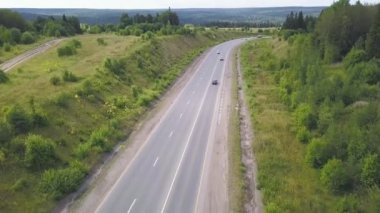 Kırsal yolun üst manzarası. Şarjör. Ormanda trafiği olan kırsal bir otoyol. Arabaları ve kamyonları olan banliyö otoyolu. Seyahat ve ulaşım