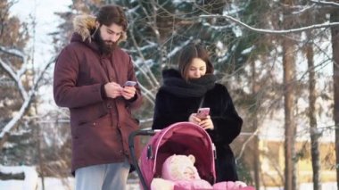 Aile çift ve bir bebek arabası kış ormandaki küçük çocuk. Evli çift manifatura üstünde onların telefon.