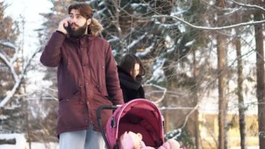 Aile çift ve bir bebek arabası kış ormandaki küçük çocuk. Bir telefon ve iletileri tipik anne baba konuşuyor.