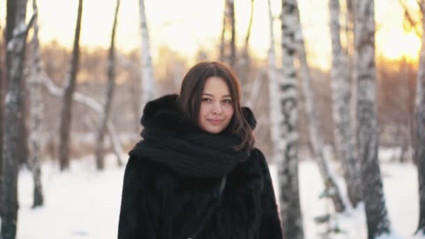 Close-up of beautiful girl in a black fur coat and scarf looking at camera. Girl is smiling. — Stock Video