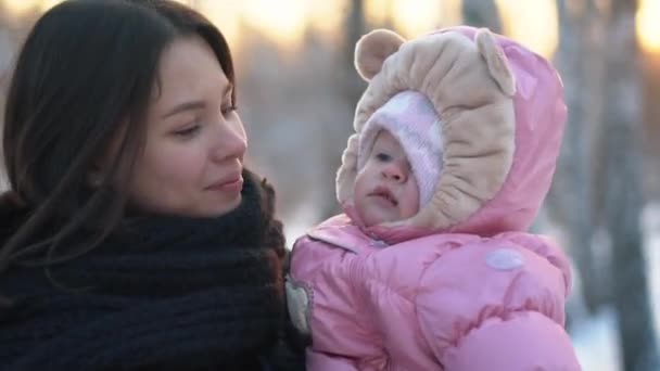 Close-up of mother holding baby girl, smiling and circling around in winter snowy forest. Happy family. — Stock Video