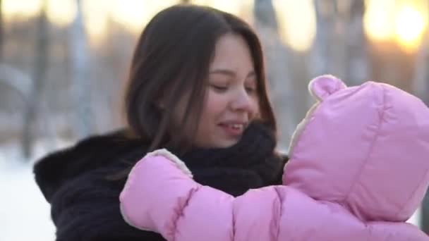 赤ちゃんの女の子 笑顔と雪に覆われた冬の森の中をのびのびを保持している母親のクローズ アップ 幸せな家族 — ストック動画