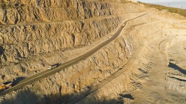 Bovenaanzicht van steengroeve met vrachtwagens. Schot. Meertraps pit muur voor mijnbouw en passeren op haar weg voor trucks en dumpers. Stapsgewijze technologie van winning van steen — Stockvideo