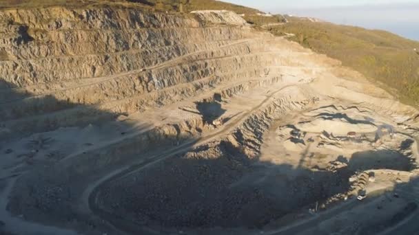 Vista superior de la cantera escalonada. Le dispararon. Cantera con camiones volquete y excavadoras. El tajo abierto funciona por la mañana. Trabajos mineros por bancos verticales abiertos — Vídeos de Stock