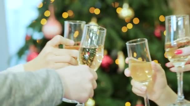 Company is holding glasses with champagne and clink, christmas tree on the background. Christmas, celebration and holidays concept - happy team clinking glasses of sparkling wine at party — Stock Video