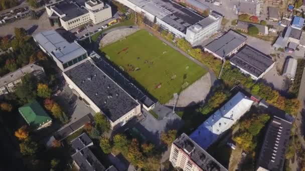 Vista aérea del estadio de fútbol con un pequeño número de jugadores. Centro ciudad . — Vídeos de Stock