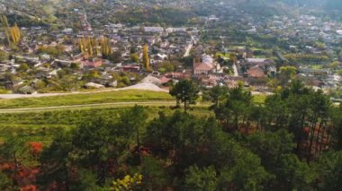 Üstten görünüm City forest yakınındaki Hills Vadisi'nde. Vurdu. Yeşil orman ve tepelerin eteklerinde şehirde sınır. Güneşli bir günde yeşil dağ kasabası. Kentsel çevre doğa yakın
