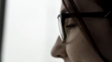 Aşırı yakın genç kadın yüzü portre profil bulanık, beyaz arka plan üzerinde siyah gözlük için. Güzel bir kadınla konuşan ve kısa, koyu renk saçlarını dokunmadan profil yüzüne.