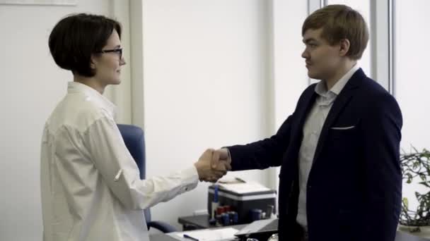 Happy, smiling co workers shaking hands standing in modern office, nice to meet you gesture, promoted to the post, reward for accomplishments. Two cheerful colleagues shaking hands in the office. — Stock Video