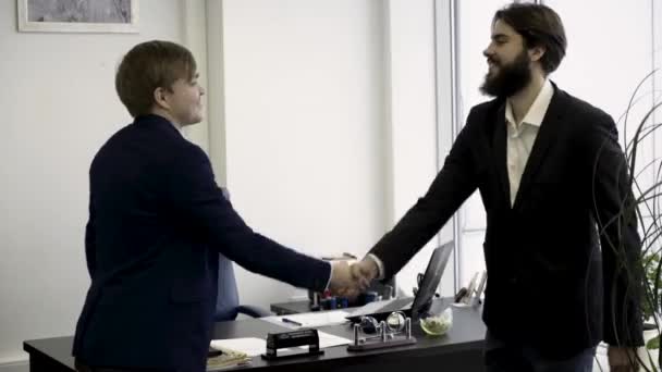 Feliz, sonrientes hombres de negocios estrechando las manos de pie en la oficina moderna, un placer conocerte gesto, promovido al puesto, recompensa por los logros. Dos colegas alegres estrechando la mano en la oficina . — Vídeos de Stock