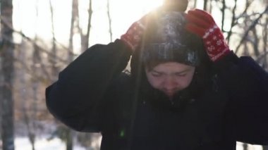 Onun hood kalktıktan ve kar kış şapkasını sallayarak bir ceketi giyen genç bir adam portresi. Yakın çekim.