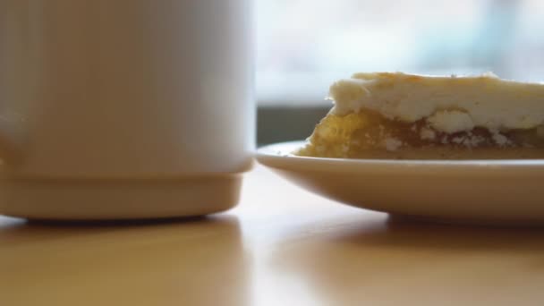 Primer plano de taza blanca y pastel en un plato en movimiento. Hora del desayuno . — Vídeo de stock