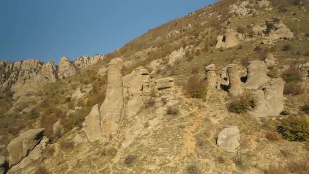 Hermoso paisaje otoñal con rocas y colinas inusuales en un día soleado. Le dispararon. Montañas con picos de formas extrañas sobre fondo de colinas amarillas marchitas . — Vídeos de Stock